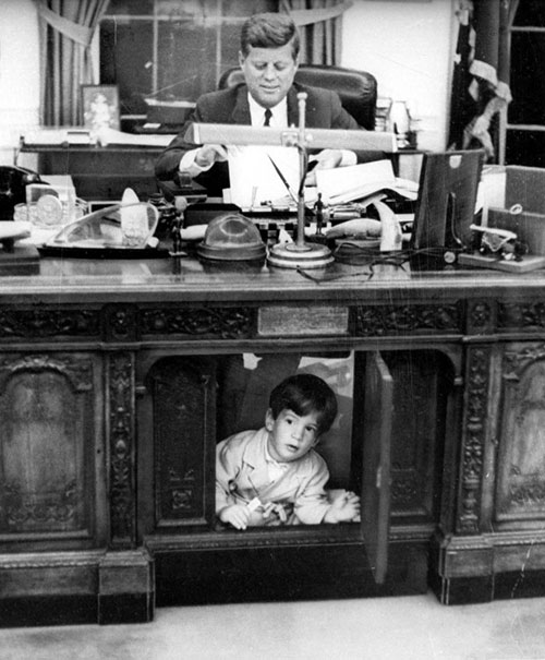 John F. Kennedy Jr. playing under John F. Kennedy's desk.
